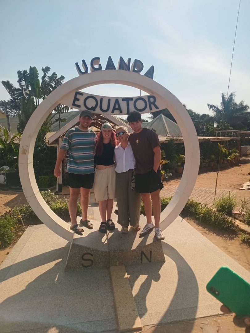 at the Ugandan equator, standing with family